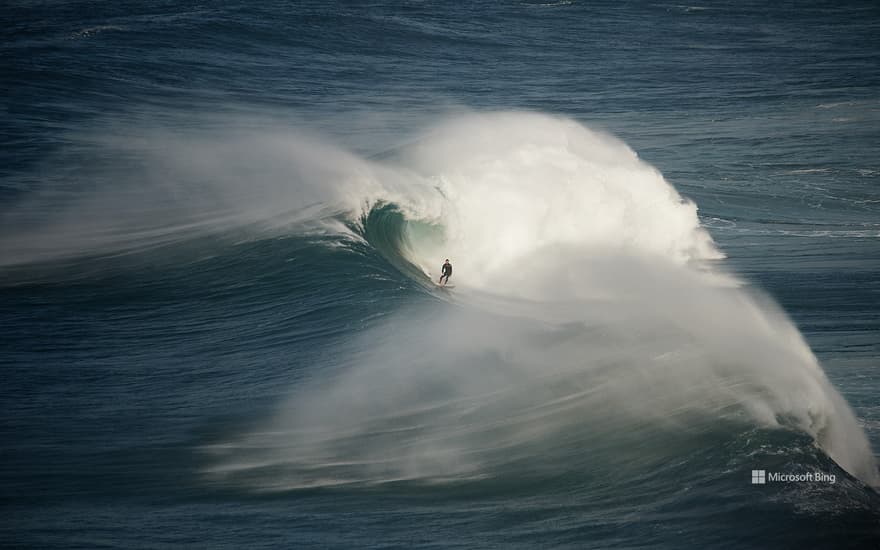 Surfer riding a wave in Nazaré, Portugal